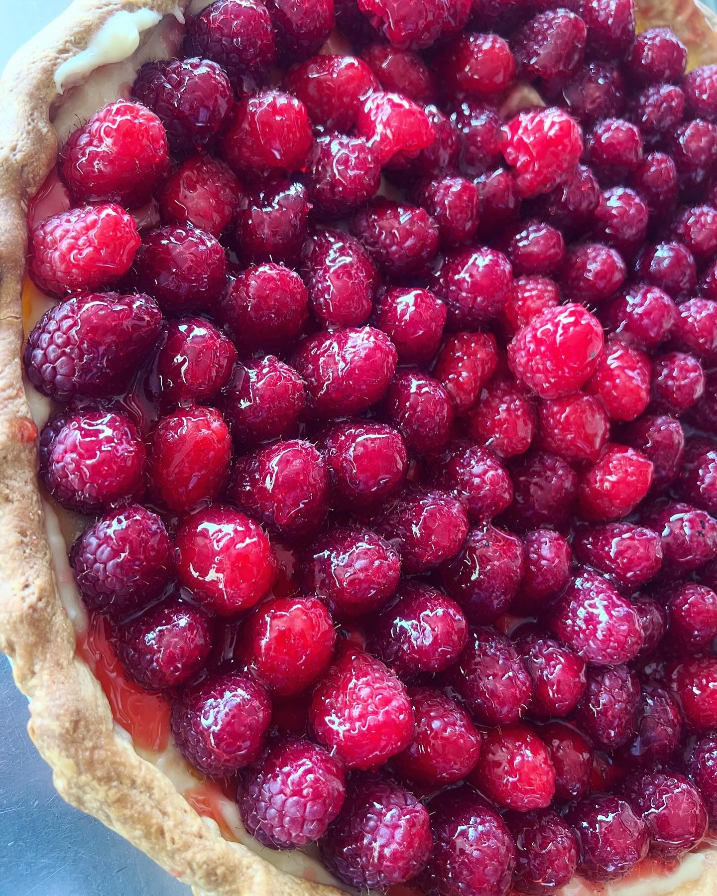 Une tarte aux framboises entières, nappée de gelée brillante